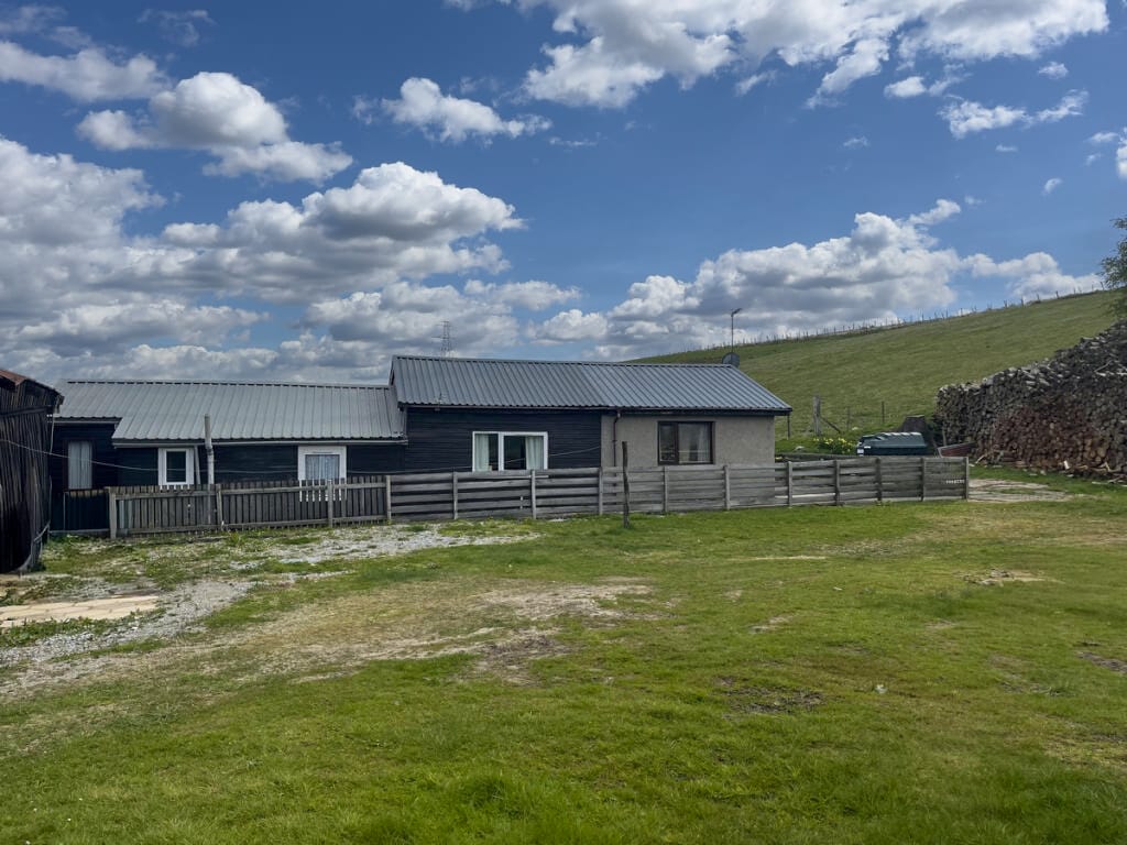 The bungalow and timber outbuildings from the yard
