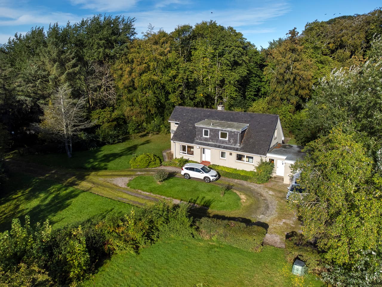 The house and horseshoe driveway in their wooded plot, from the air