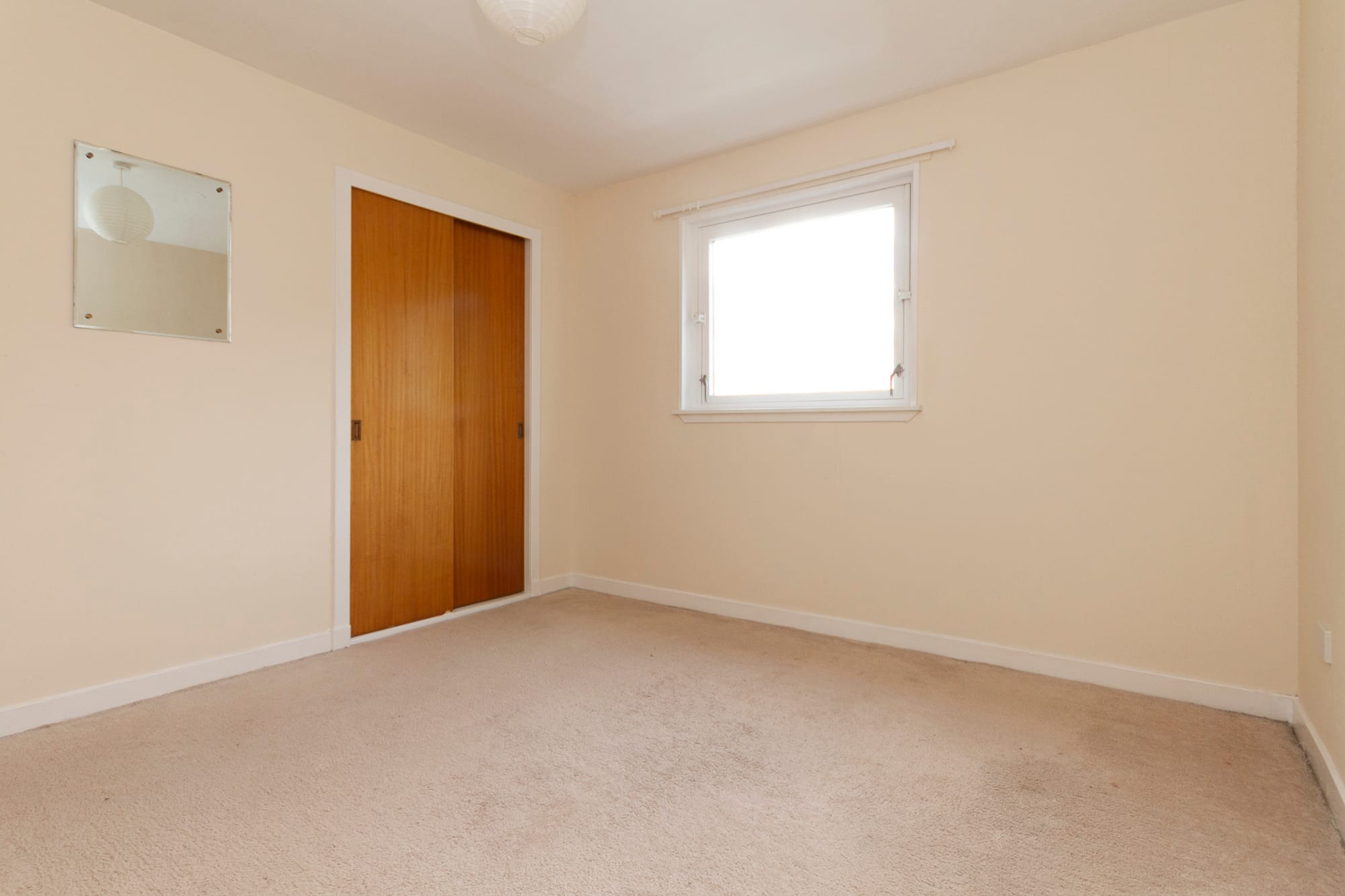 A bedroom with a window and fitted cupboard